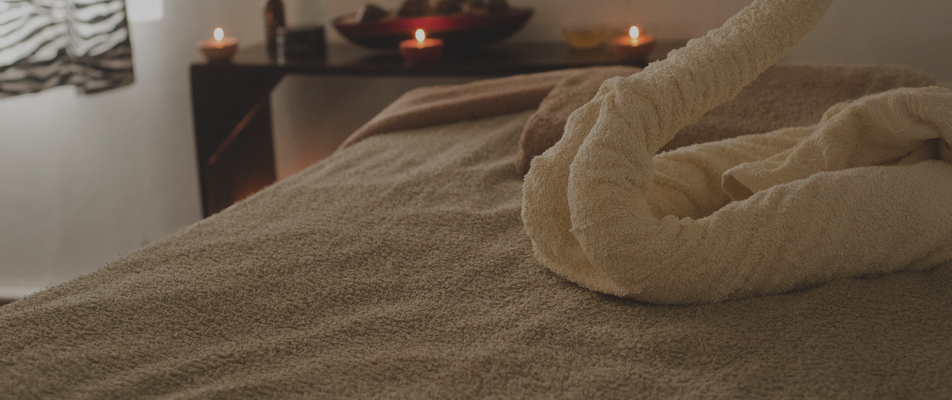 A towel on the bed with candles in the background